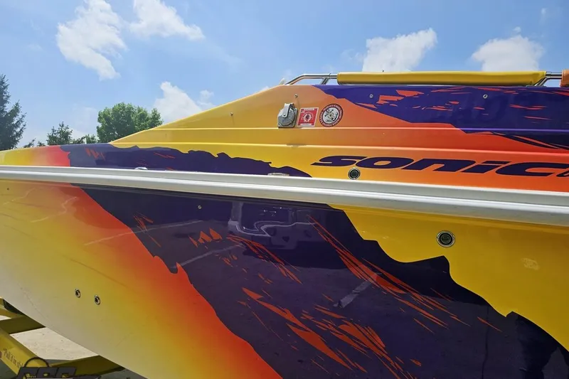 Slide: The Image of Colorful 2003 Sonic USA 31SS boat with vibrant graphics under a clear blue sky. - 21