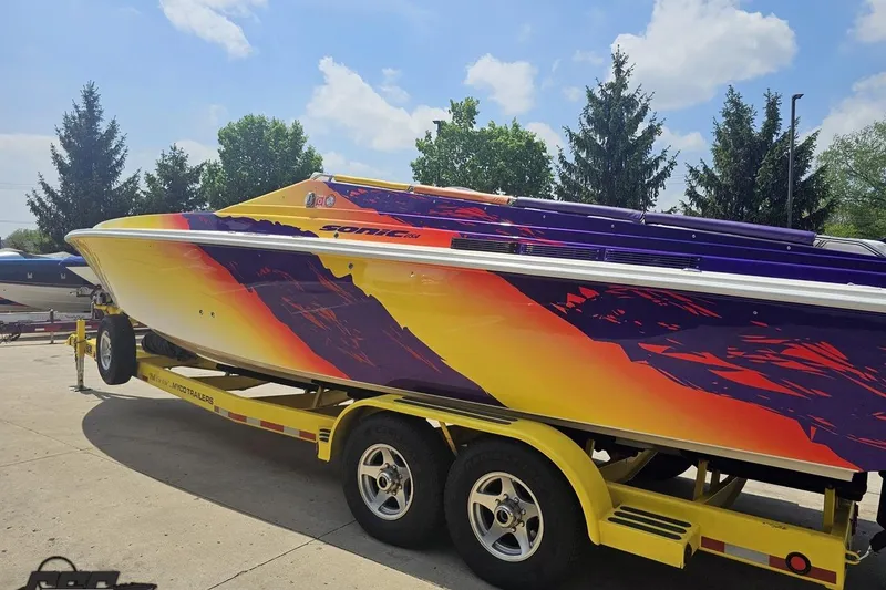Slide: The Image of 2003 Sonic USA 31SS speedboat with vibrant yellow and purple design on a trailer. - 23