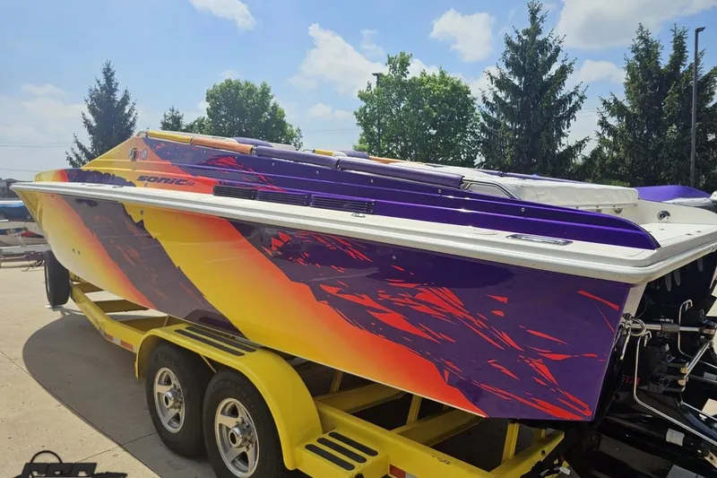Slide: The Image of Colorful 2003 Sonic USA 31SS speedboat on a yellow trailer, vibrant graphics, sunny day. - 24