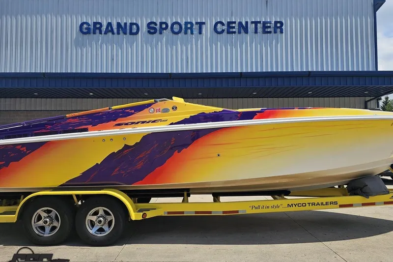 Slide: The Image of 2003 Sonic USA 31SS speedboat with vibrant graphics on a trailer at Grand Sport Center. - 3
