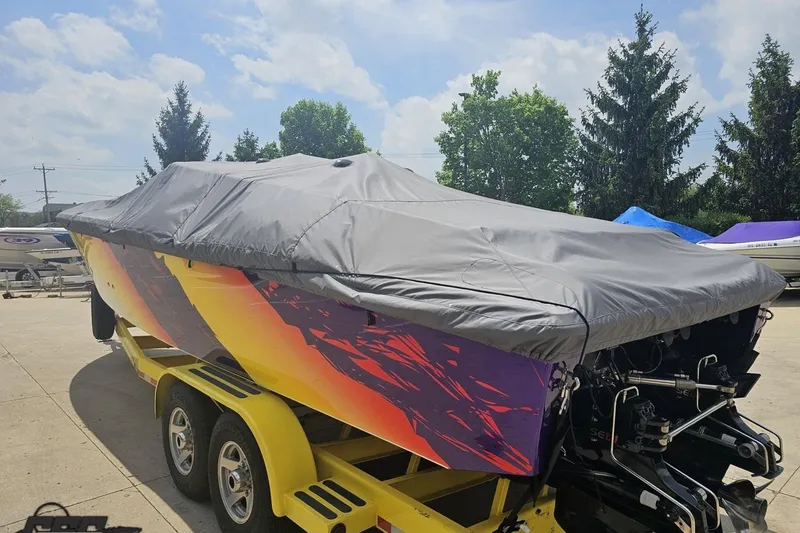 Slide: The Image of 2003 Sonic USA 31SS boat with vibrant graphics, covered and on a yellow trailer. - 31