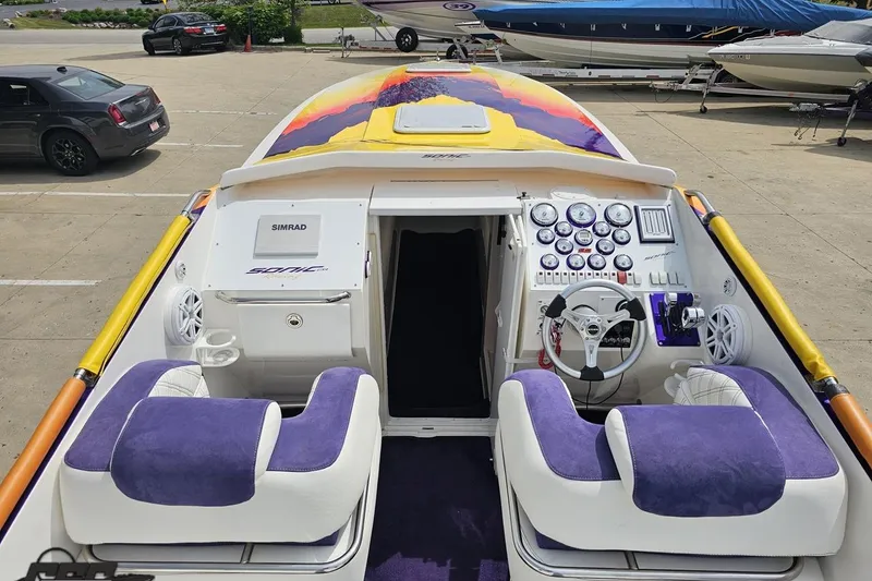 Slide: The Image of 2003 Sonic USA 31SS speedboat with vibrant seating and detailed dashboard in a parking area. - 52