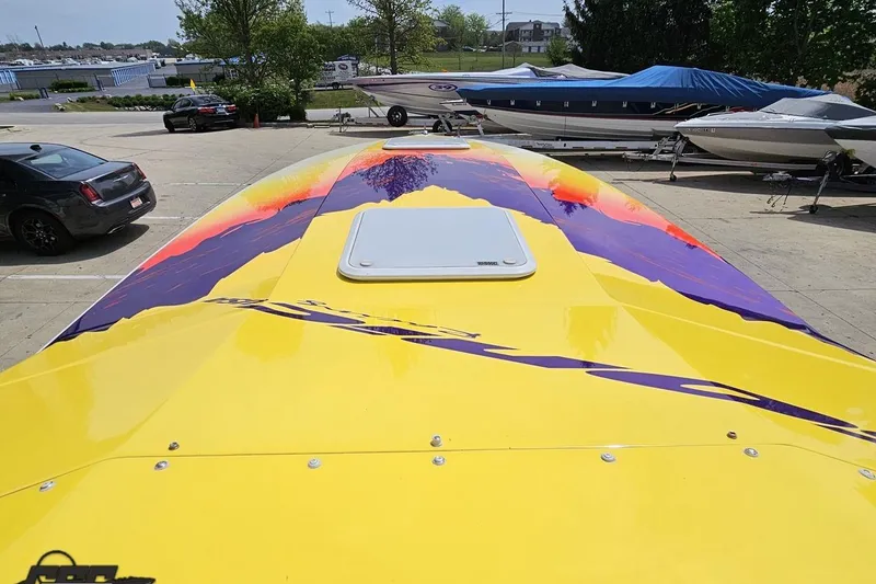 Slide: The Image of Yellow 2003 Sonic USA 31SS boat with vibrant purple and orange graphics on deck. - 69