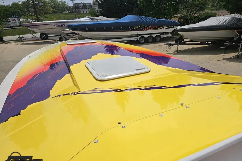 Slide: The Image of 2003 Sonic USA 31SS boat with vibrant yellow and purple design, parked outdoors. - 70