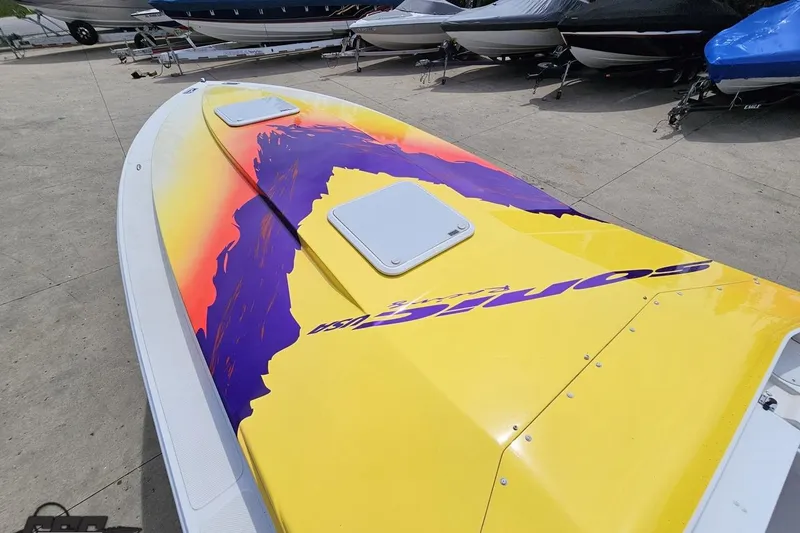 Slide: The Image of 2003 Sonic USA 31SS speedboat with vibrant yellow and purple design, docked outdoors. - 71