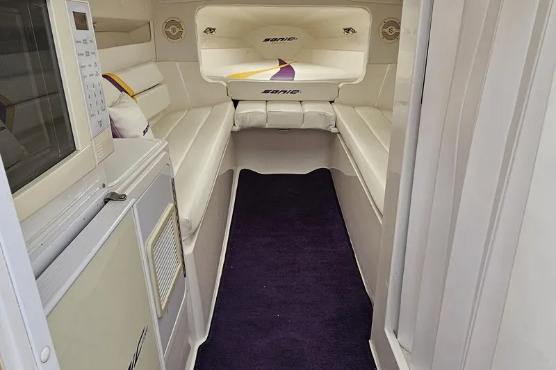 Slide: The Image of Interior of a 2003 Sonic USA 31SS boat with white seating and a microwave. - 76
