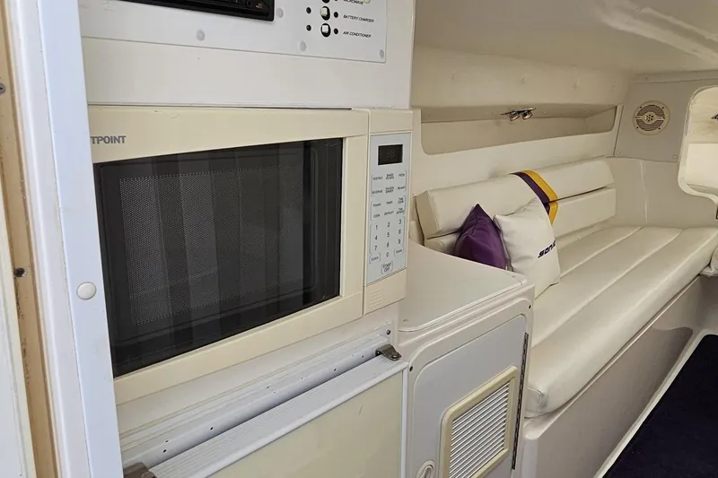Slide: The Image of Interior of a 2003 Sonic USA 31SS boat with microwave and white seating area. - 77