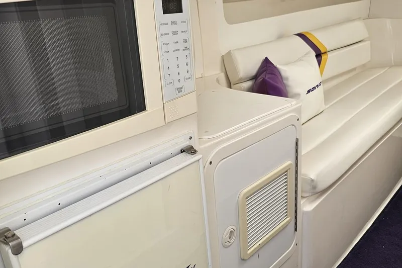 Slide: The Image of Interior of 2003 Sonic USA 31SS boat with microwave and white seating area. - 79