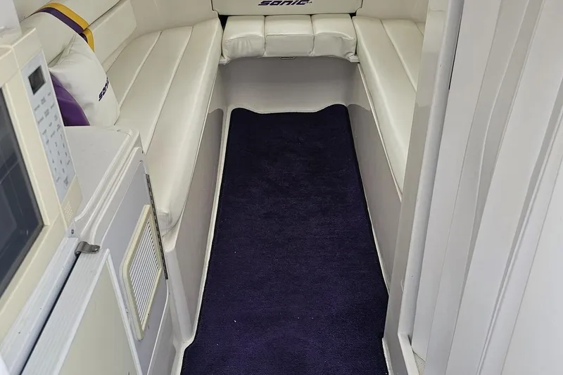 Slide: The Image of Interior of a 2003 Sonic USA 31SS boat with white seating and a dark carpet. - 80