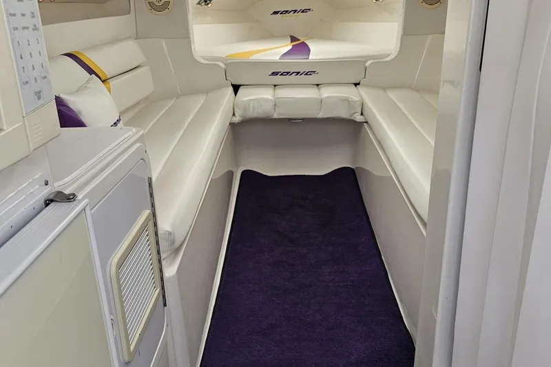Slide: The Image of Interior of a 2003 Sonic USA 31SS boat with white seating and purple accents. - 81