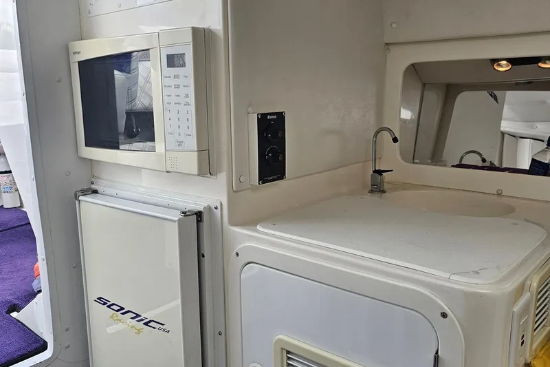 Slide: The Image of 2003 Sonic USA 31SS interior with microwave, sink, and compact fridge. - 84
