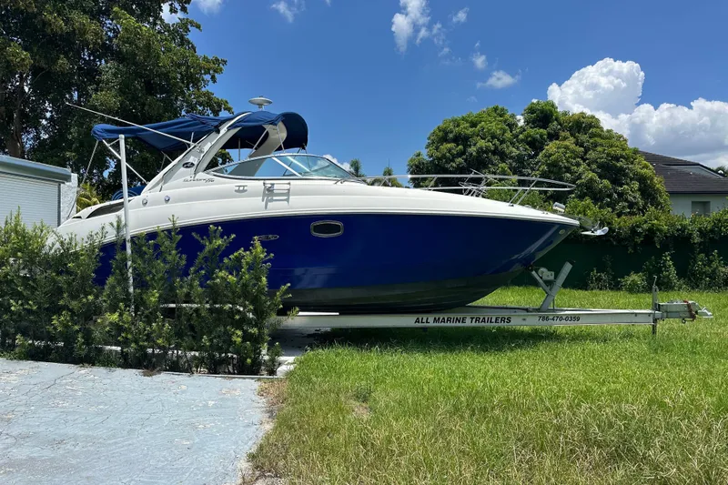 Slide: The Image of 2009 Sea Ray 270 Sundancer boat on trailer, parked in grassy area under blue sky. - 12