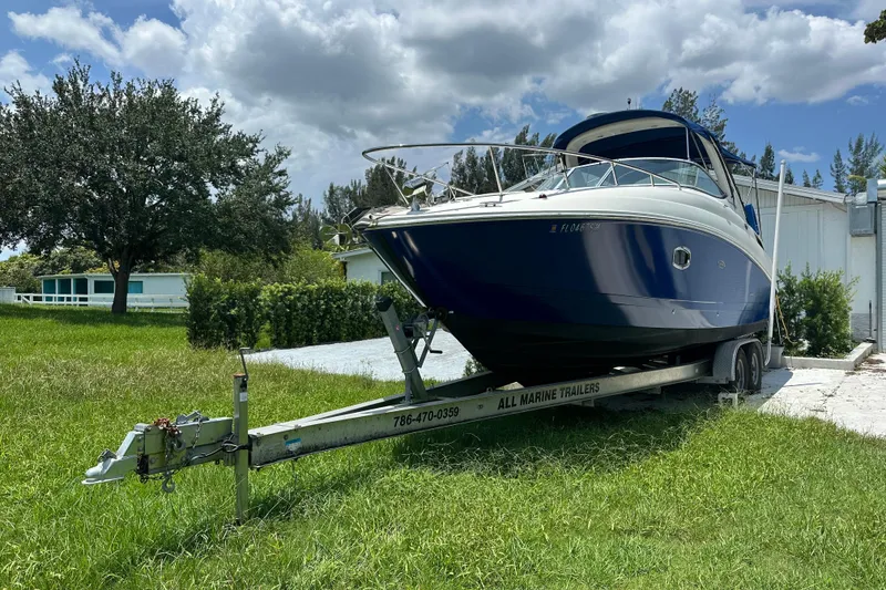 Slide: The Image of 2009 Sea Ray 270 Sundancer boat on trailer, parked on grassy area under cloudy sky. - 15