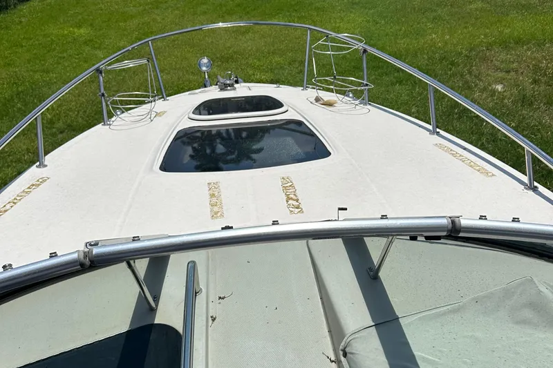 Slide: The Image of 2009 Sea Ray 270 Sundancer boat deck with railing and hatches, grassy background. - 5