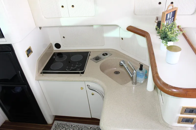 Slide: The Image of 1997 Sea Ray 400 Sedan Bridge kitchen with stove, sink, and decor. - 15