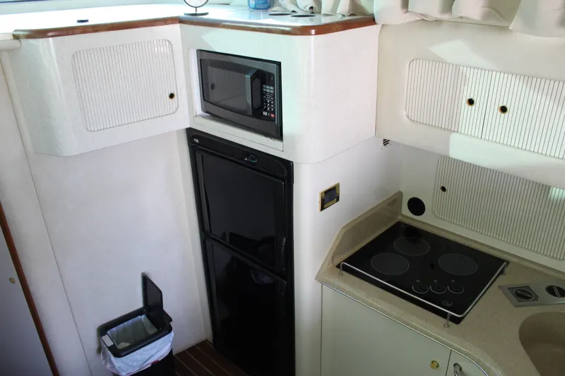 Slide: The Image of 1997 Sea Ray 400 Sedan Bridge kitchen with microwave, stove, and refrigerator. - 16
