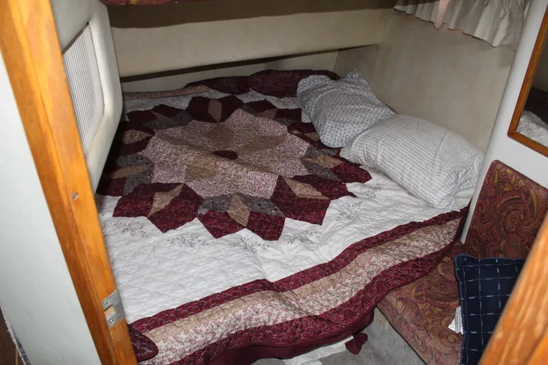 Slide: The Image of Cozy cabin bedroom in 1997 Sea Ray 400 Sedan Bridge with patterned quilt and pillows. - 27
