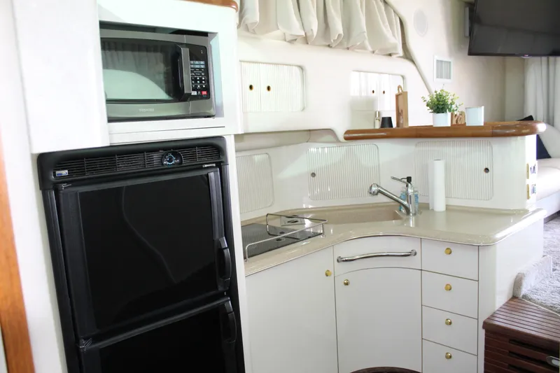 Slide: The Image of 1997 Sea Ray 400 Sedan Bridge kitchen with microwave, fridge, and sink. - 28