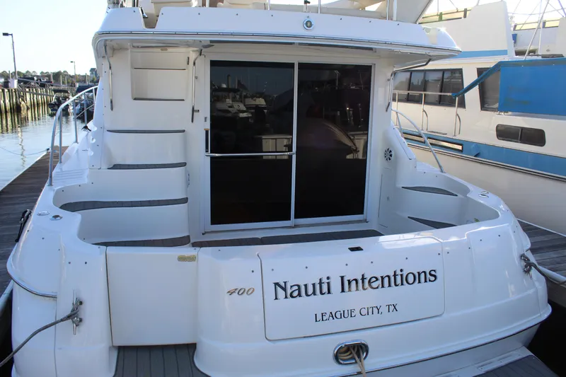 Slide: The Image of 1997 Sea Ray 400 Sedan Bridge yacht docked, rear view with "Nauti Intentions" name. - 3