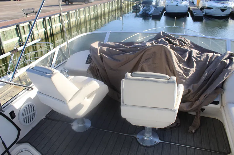 Slide: The Image of 1997 Sea Ray 400 Sedan Bridge cockpit with covered equipment and two white seats. - 35