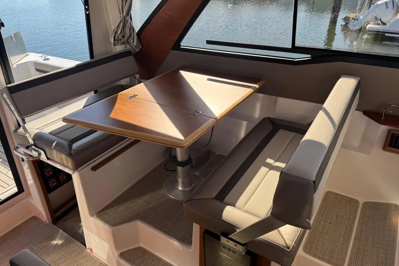 Slide: The Image of Interior of 2026 Cutwater C-288 Coupe featuring a cozy dining area with a wooden table. - 13