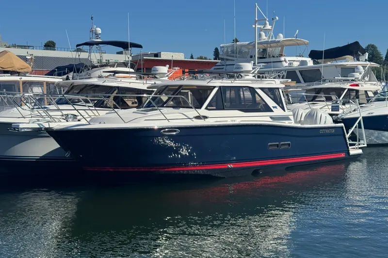 Slide: The Image of 2026 Cutwater C-288 Coupe docked at marina, surrounded by other boats. - 2