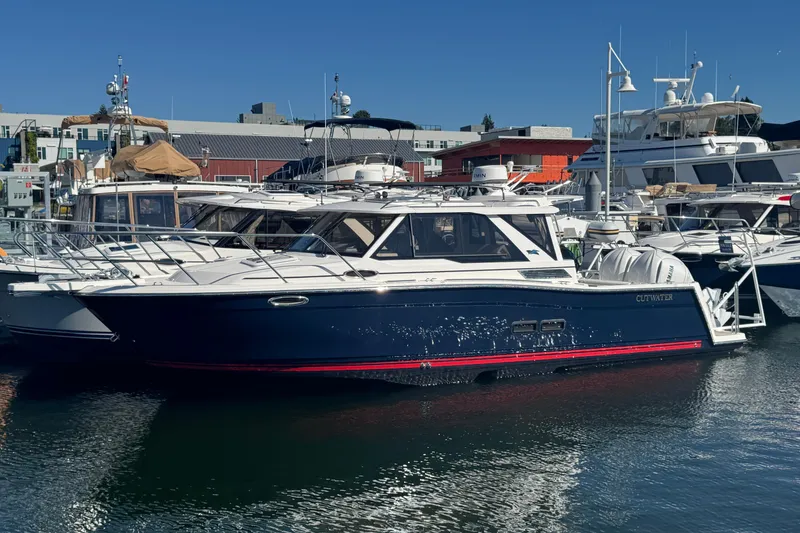 Slide: The Image of 2026 Cutwater C-288 Coupe boat docked in a marina, surrounded by other vessels. - 3