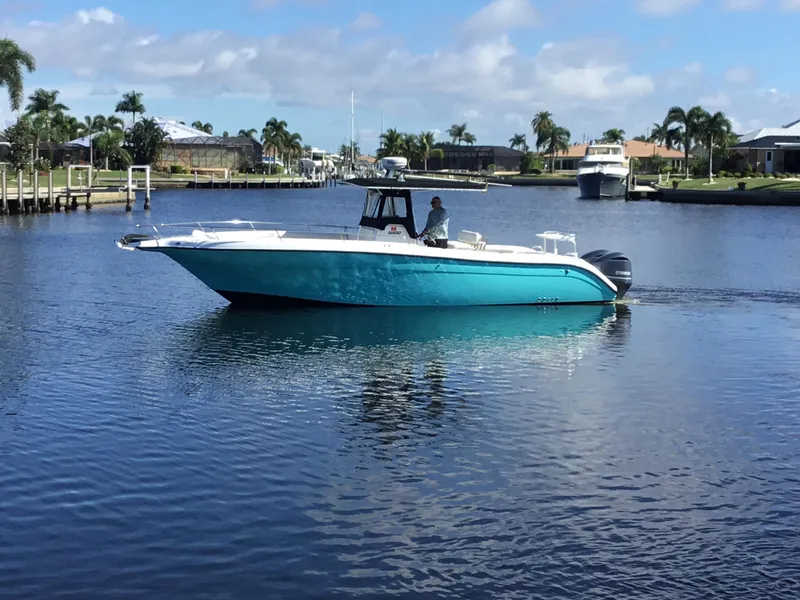 Slide: The Image of 2004 Century 3200 Center Console boat on calm water, surrounded by palm trees and houses. - 0
