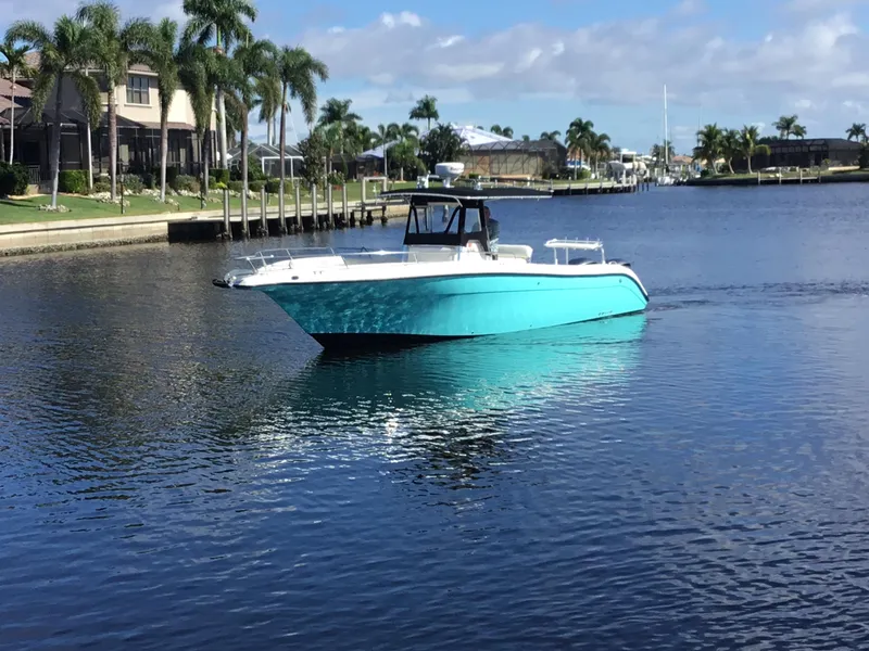 Slide: The Image of 2004 Century 3200 Center Console boat on a calm waterway, surrounded by palm trees. - 2
