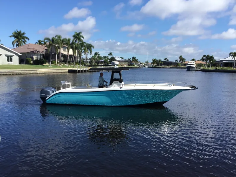 Slide: The Image of 2004 Century 3200 Center Console boat cruising on a sunny waterfront with palm trees. - 6
