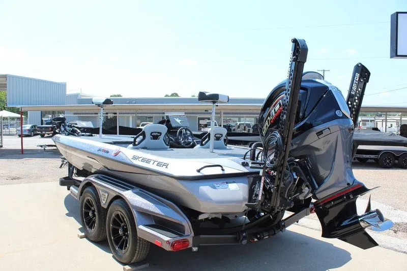 Slide: The Image of 2026 Skeeter FXR20 FLEX bass boat on trailer, parked outside a building. - 1