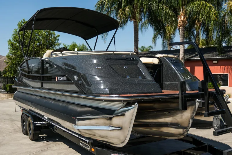 Slide: The Image of 2018 Crest Savannah 250 SLS pontoon boat on trailer, parked near palm trees. - 2