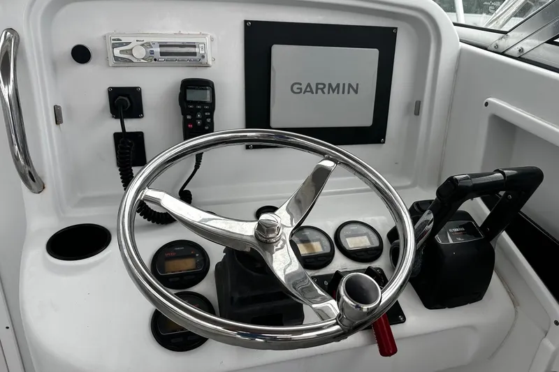 Slide: The Image of 2006 Glacier Bay 2670 boat helm with steering wheel and cushioned captain's chair. - 11