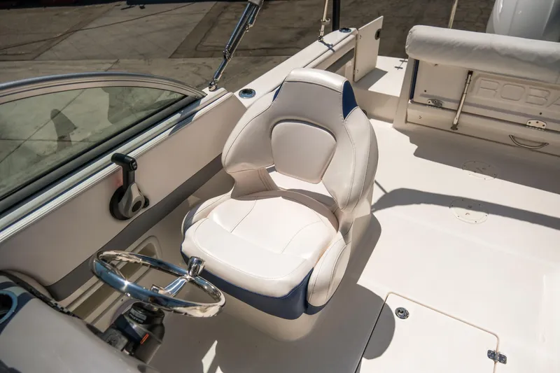Slide: The Image of 2021 Robalo R227 Dual Console boat interior with white captain's chair and steering wheel. - 16