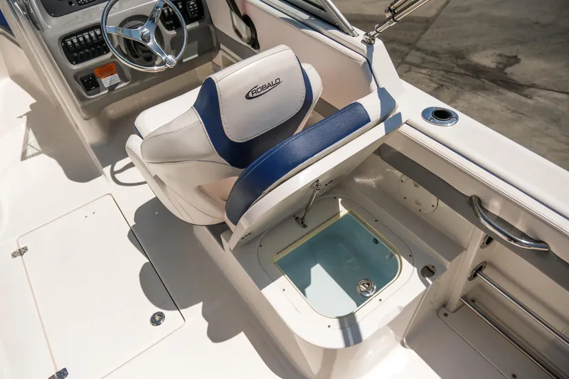 Slide: The Image of 2021 Robalo R227 Dual Console boat interior with helm seat and storage compartment. - 19