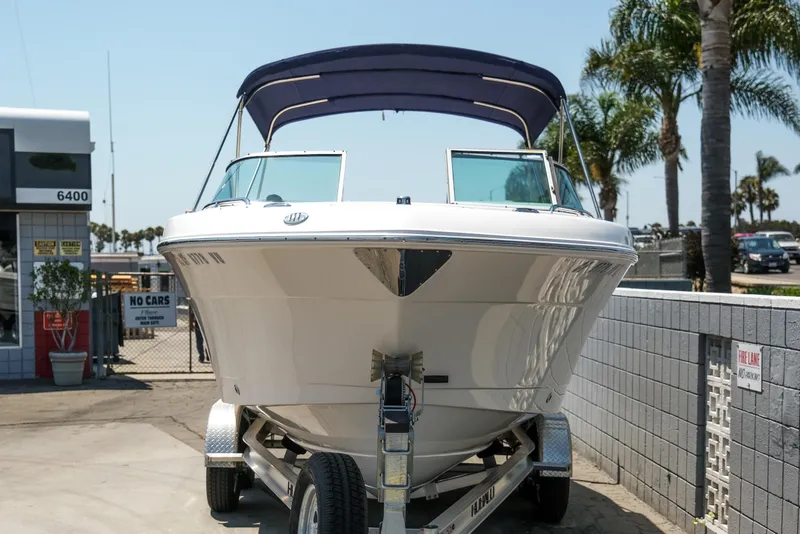 Slide: The Image of 2021 Robalo R227 Dual Console boat on trailer, parked outdoors near palm trees. - 2