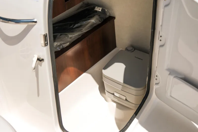 Slide: The Image of 2021 Robalo R227 Dual Console interior with portable toilet and storage area. - 21