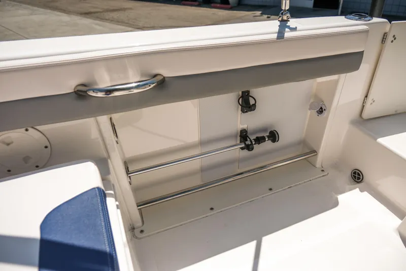 Slide: The Image of 2021 Robalo R227 Dual Console boat interior, featuring storage compartment and stainless steel railing. - 23