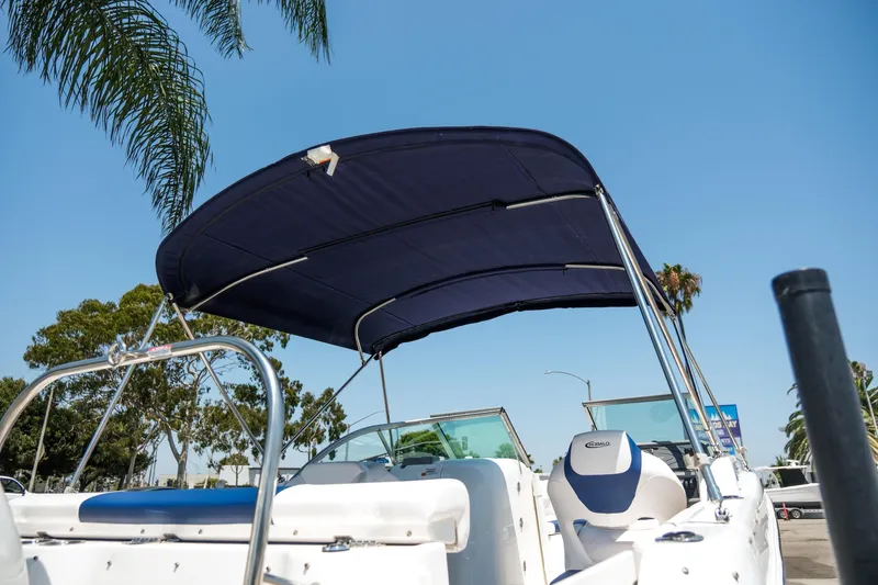 Slide: The Image of 2021 Robalo R227 Dual Console boat with blue canopy, parked under clear sky. - 30