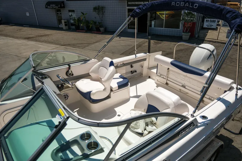 Slide: The Image of 2021 Robalo R227 Dual Console boat with white and blue seating, docked outdoors. - 8
