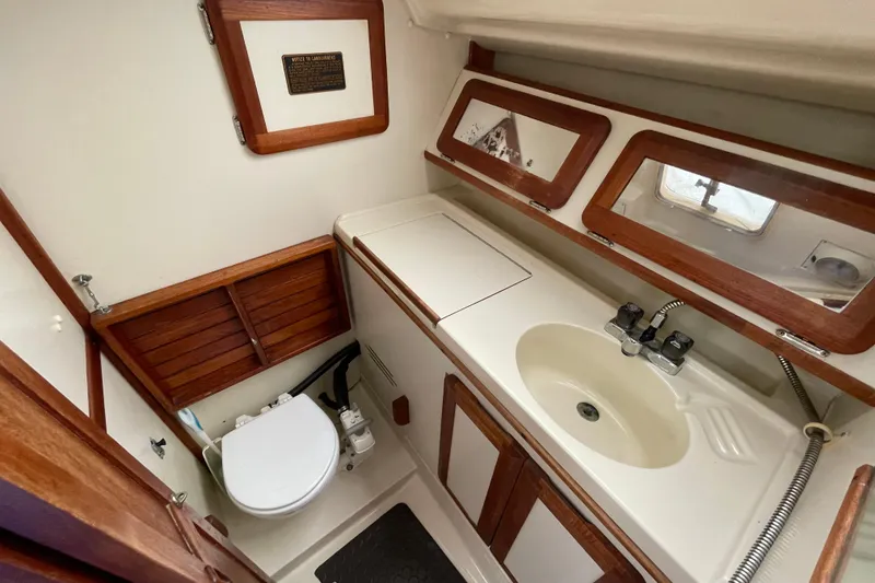 Slide: The Image of 1994 Hunter 30 yacht bathroom with wooden accents, sink, and toilet. - 13