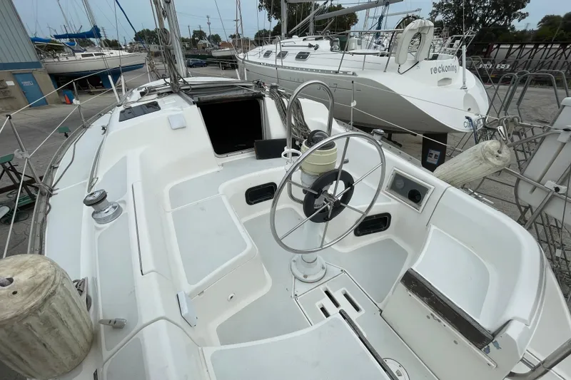 Slide: The Image of 1994 Hunter 30 sailboat cockpit with steering wheel, docked alongside other boats. - 7