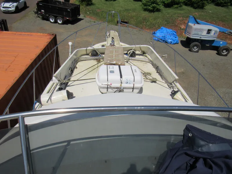 Slide: The Image of 1989 Tollycraft Sport Sedan boat deck with equipment, parked near containers and machinery. - 22