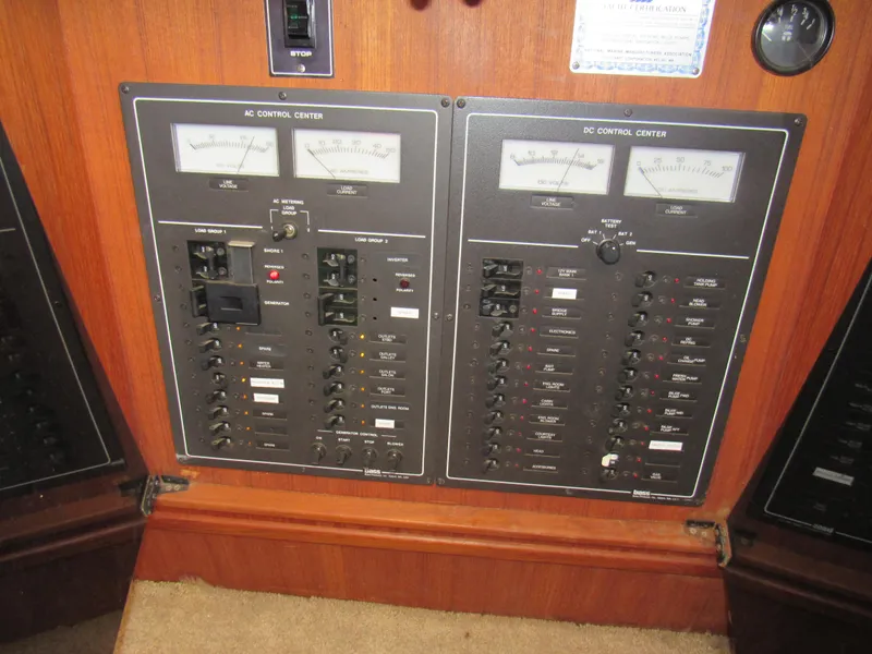 Slide: The Image of 1989 Tollycraft Sport Sedan DC control panel with gauges and switches on wooden background. - 23