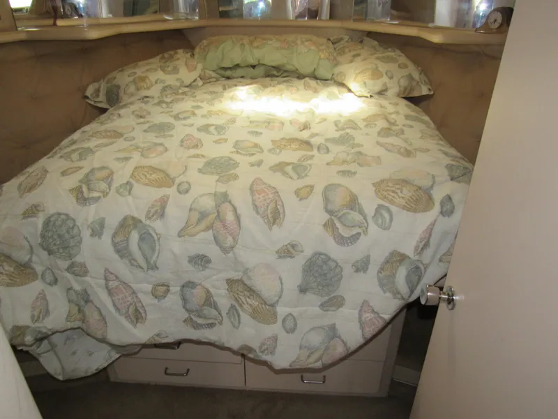 Slide: The Image of 1989 Tollycraft Sport Sedan bedroom with seashell-patterned bedding and under-bed storage. - 25