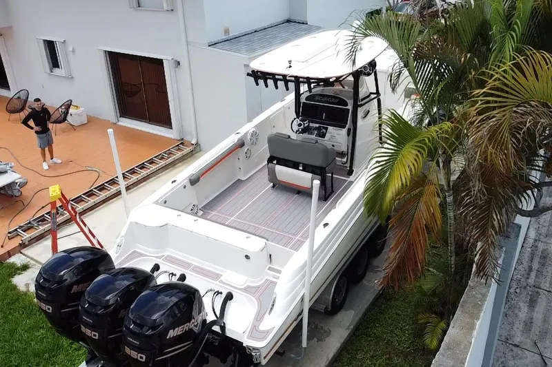 Slide: The Image of 2007 Scarab 35 Sport boat with triple Mercury engines, parked near a house and palm trees. - 31