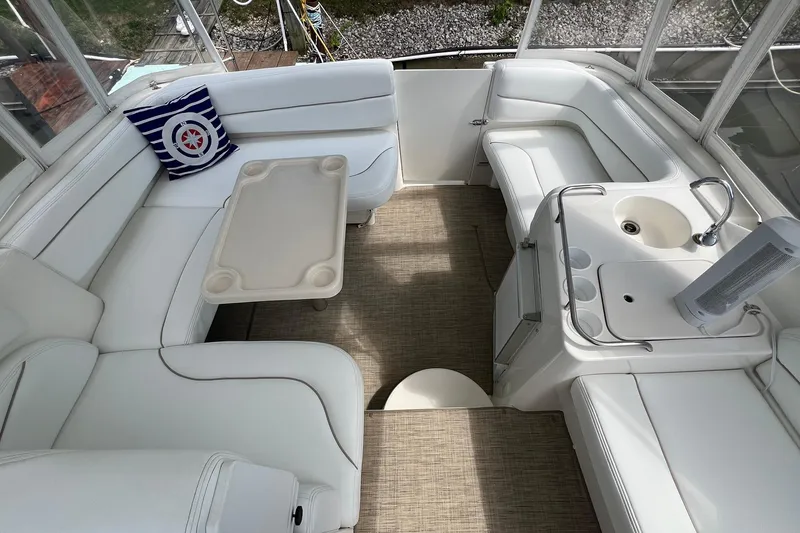 The Image of 2000 Larson 330 Cabrio boat docked in marina, featuring white exterior and covered seating area. - 0