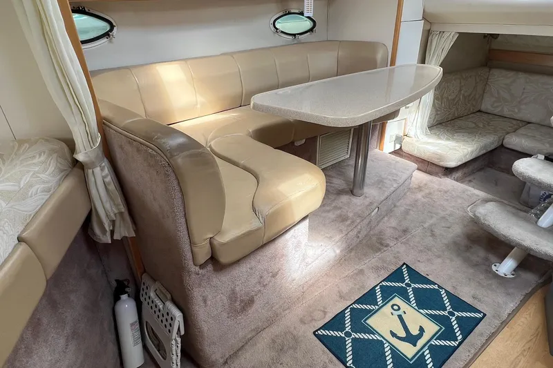 Slide: The Image of Interior of a 2000 Larson 330 Cabrio boat with beige seating and anchor-themed rug. - 11