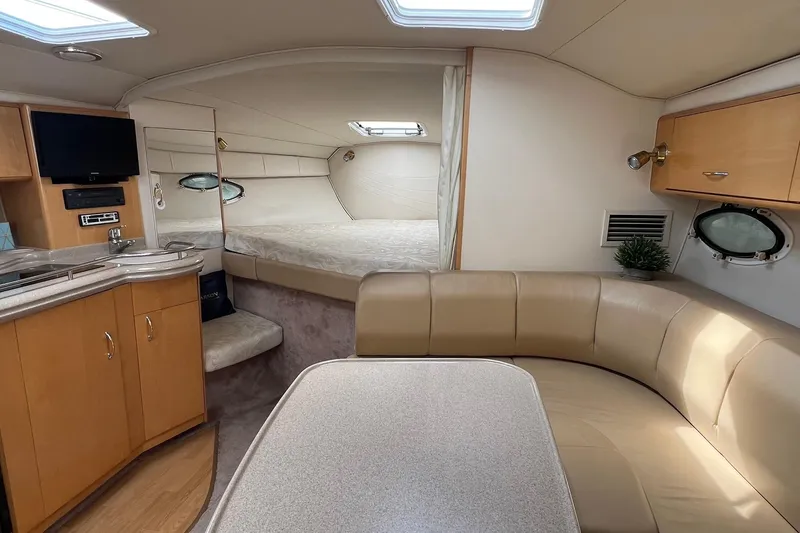 Slide: The Image of 2000 Larson 330 Cabrio cabin interior with cozy seating, kitchenette, and sleeping area. - 20