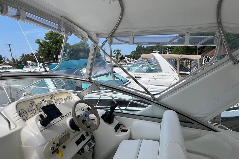 Slide: The Image of 2000 Larson 330 Cabrio boat docked, featuring spacious seating and clear canopy. - 5